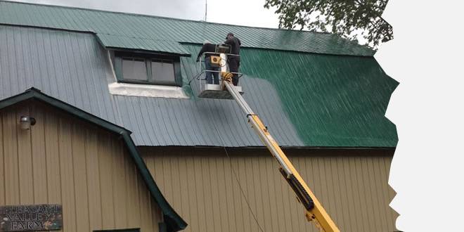 A man on a crane is working on the roof of a building.