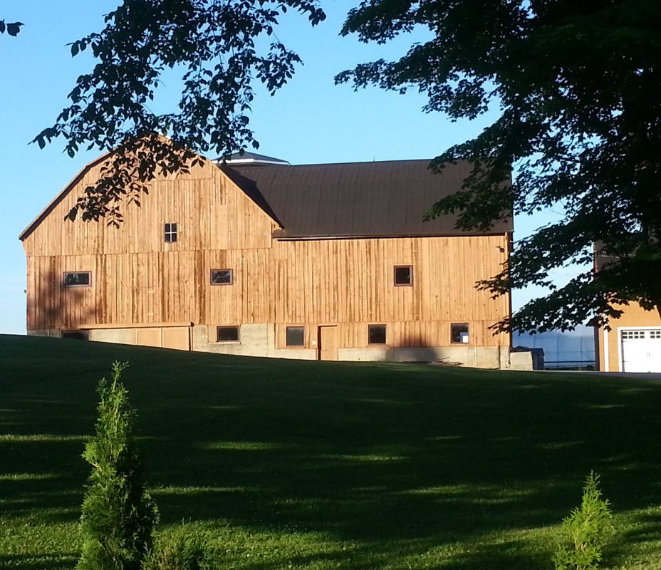 A large barn sitting on top of a green hillside.