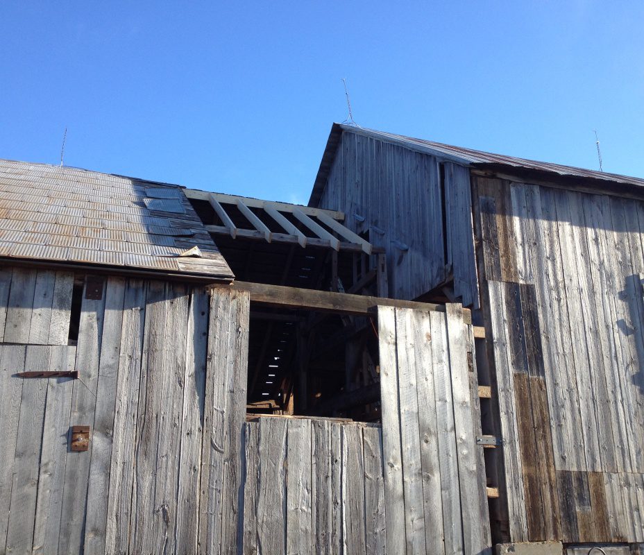 A barn with an open window and a broken roof.