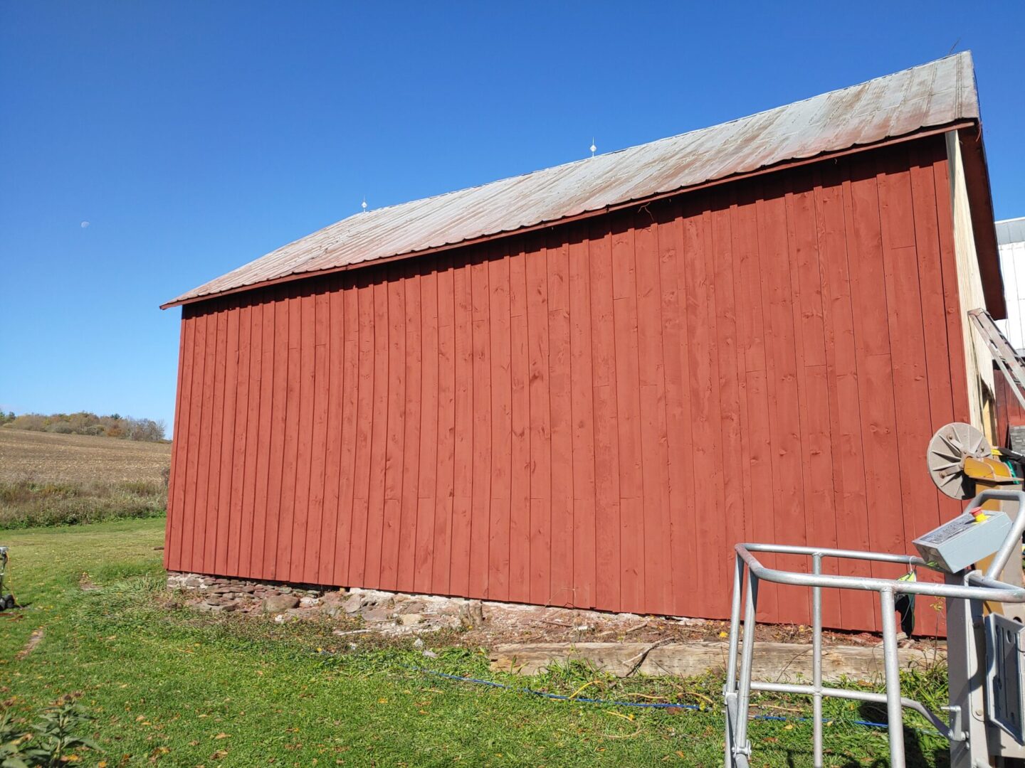 A red barn with a metal roof and grass